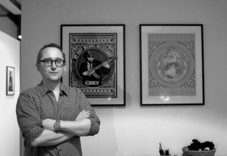 Matthew Fargher at home in front of his Shepard Fairey prints. Image: &copy; Florence Early